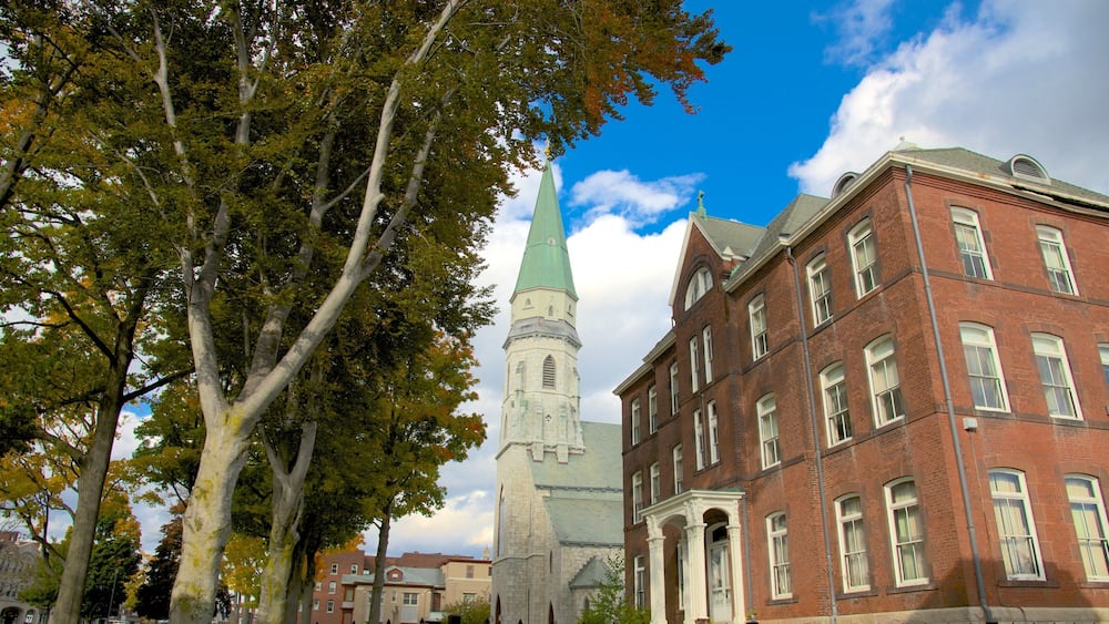 A church with a green spire and a red brick building with arched windows.