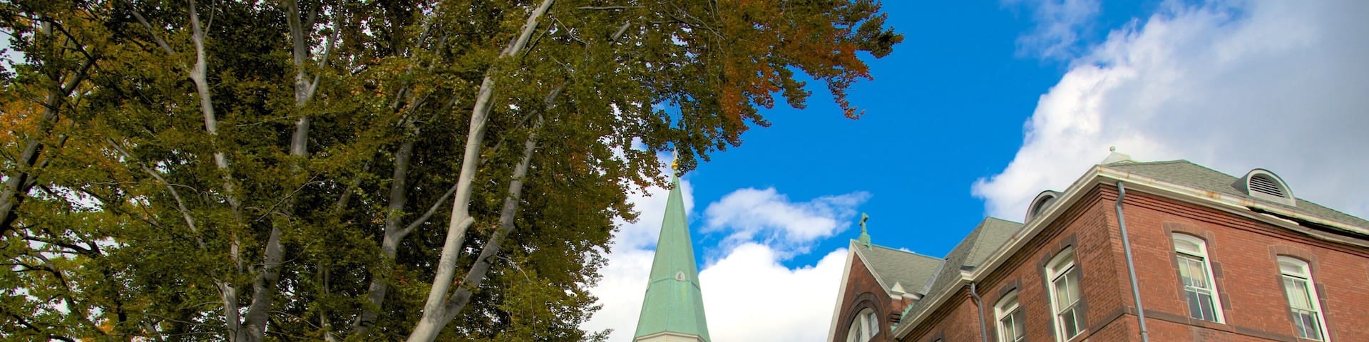 A church with a green spire and a red brick building with arched windows.