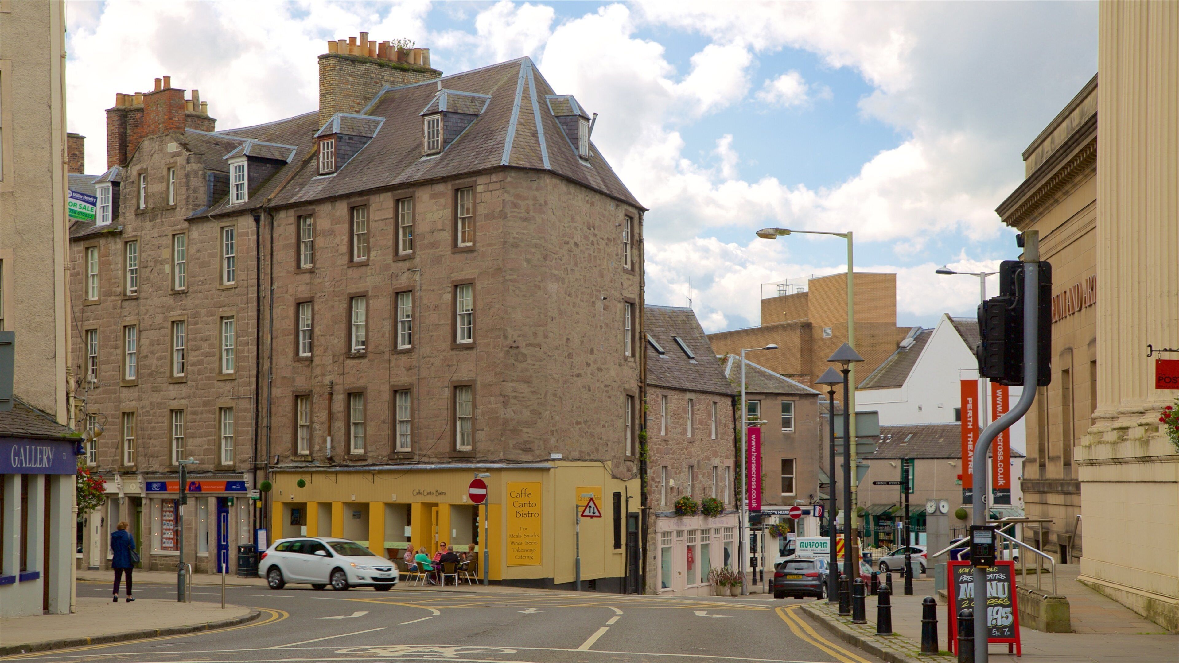 A street with a historic building, a cafe, and a traffic light.