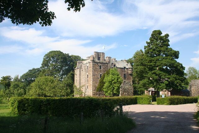 A historic stone castle surrounded by lush greenery and trees.