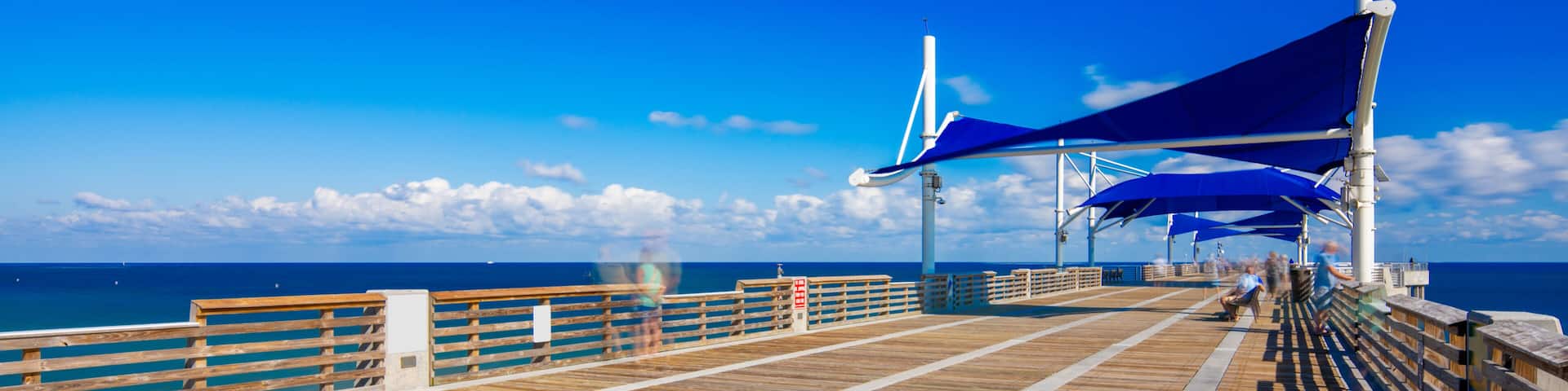 Pompano Beach Fishing Pier over the Atlantic Ocean. Long exposure to blur clouds and people