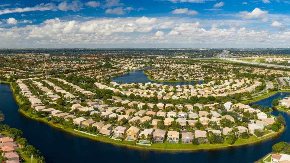A residential area with a river meandering through it, surrounded by houses and greenery.