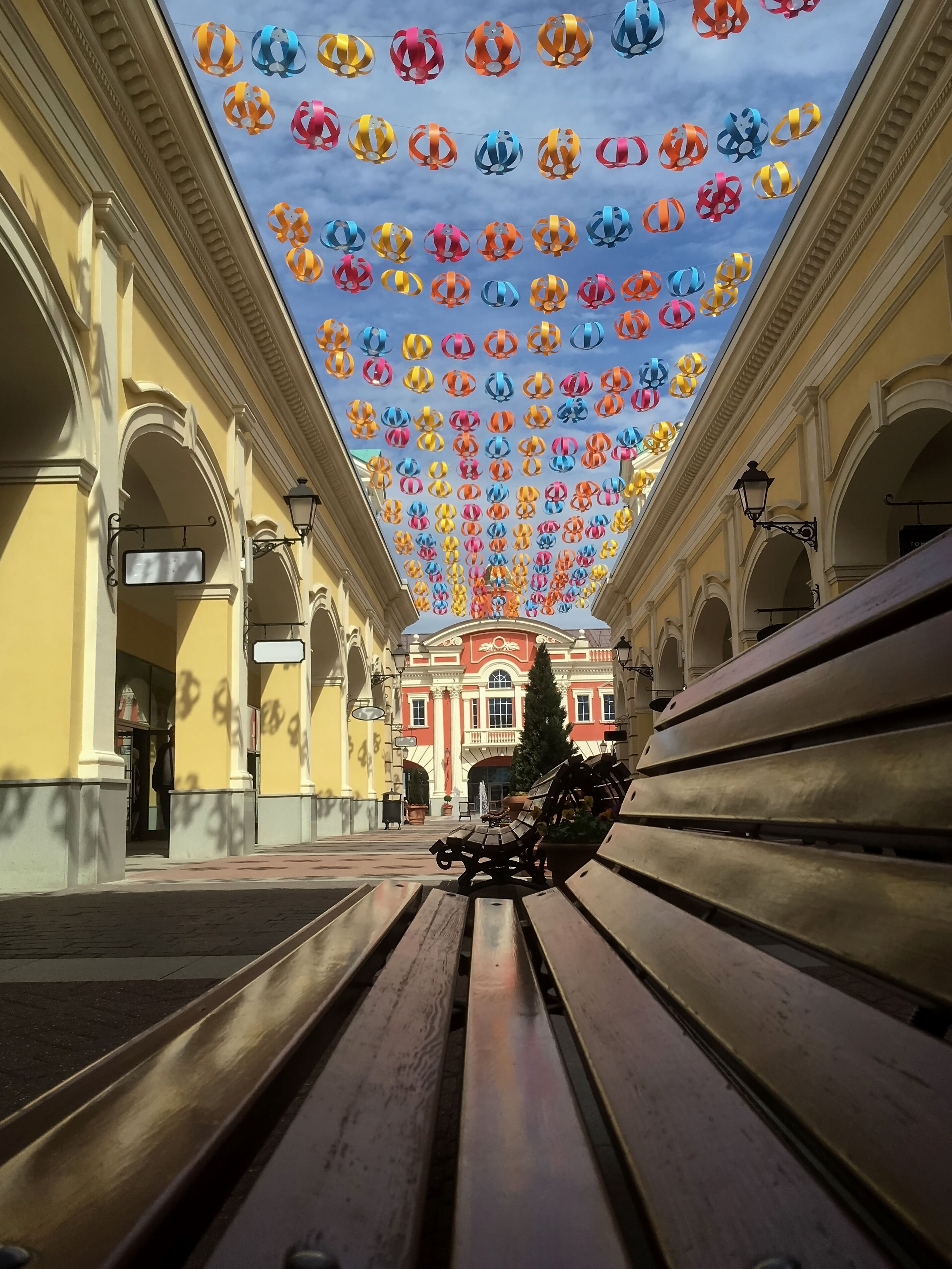 A street with benches and a building with a colorful ceiling.