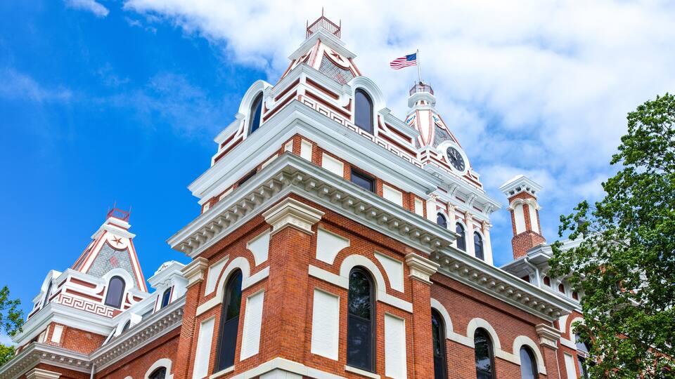 A historic building with ornate architecture, a clock tower, and an American flag.
