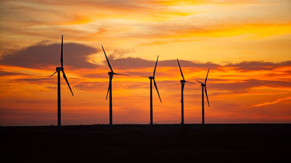 Wind turbines silhouetted against a sunset sky.