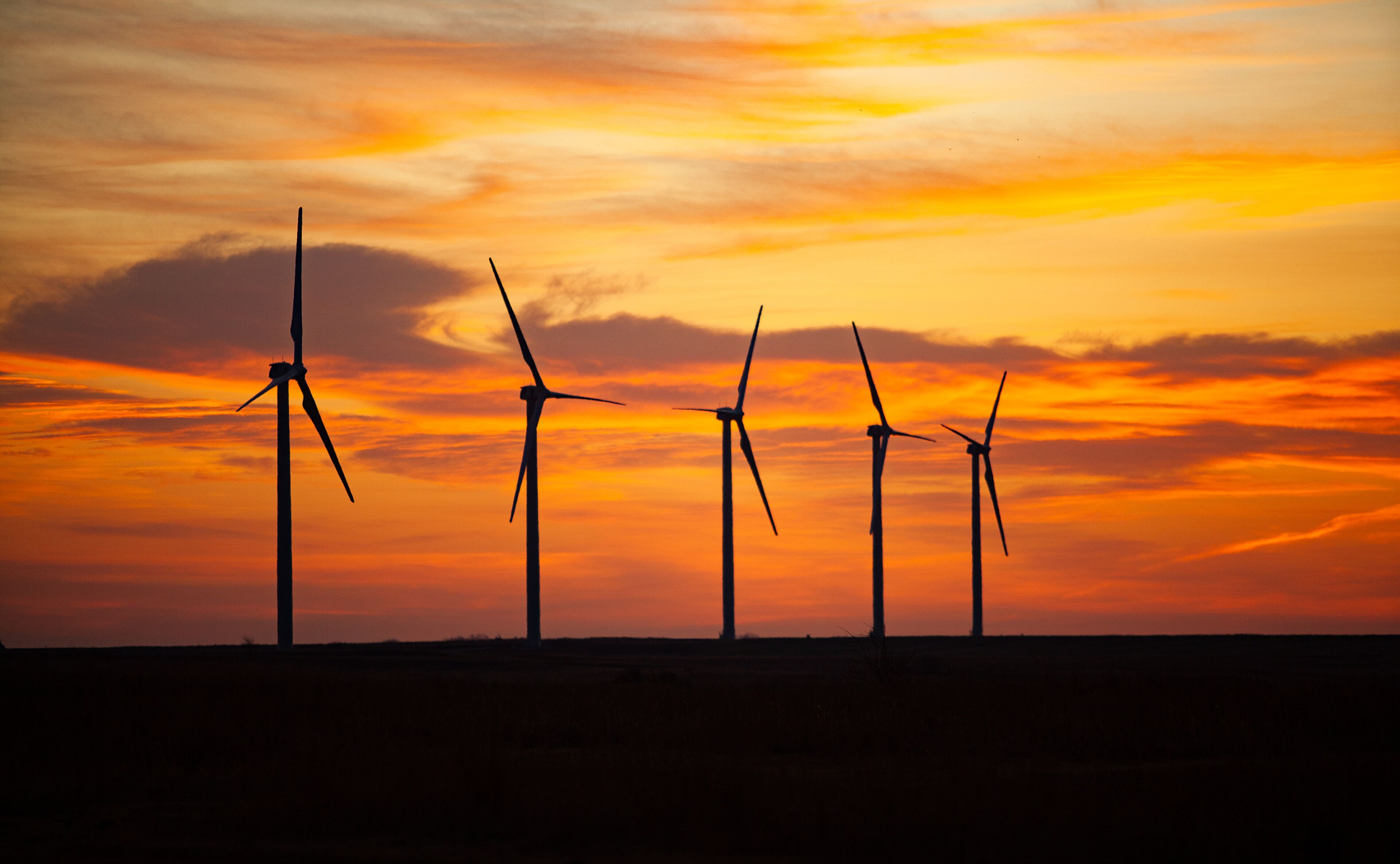 Wind turbines silhouetted against a sunset sky.