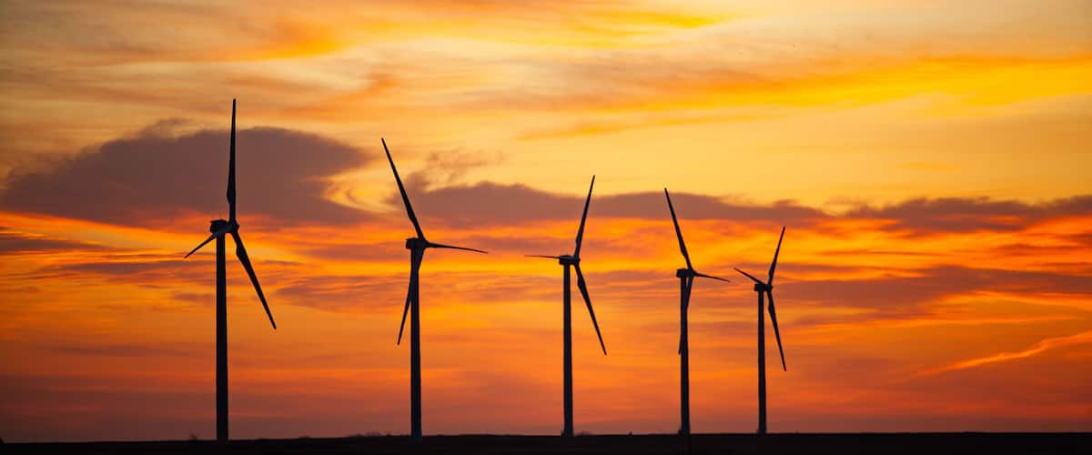 Wind turbines silhouetted against a sunset sky.