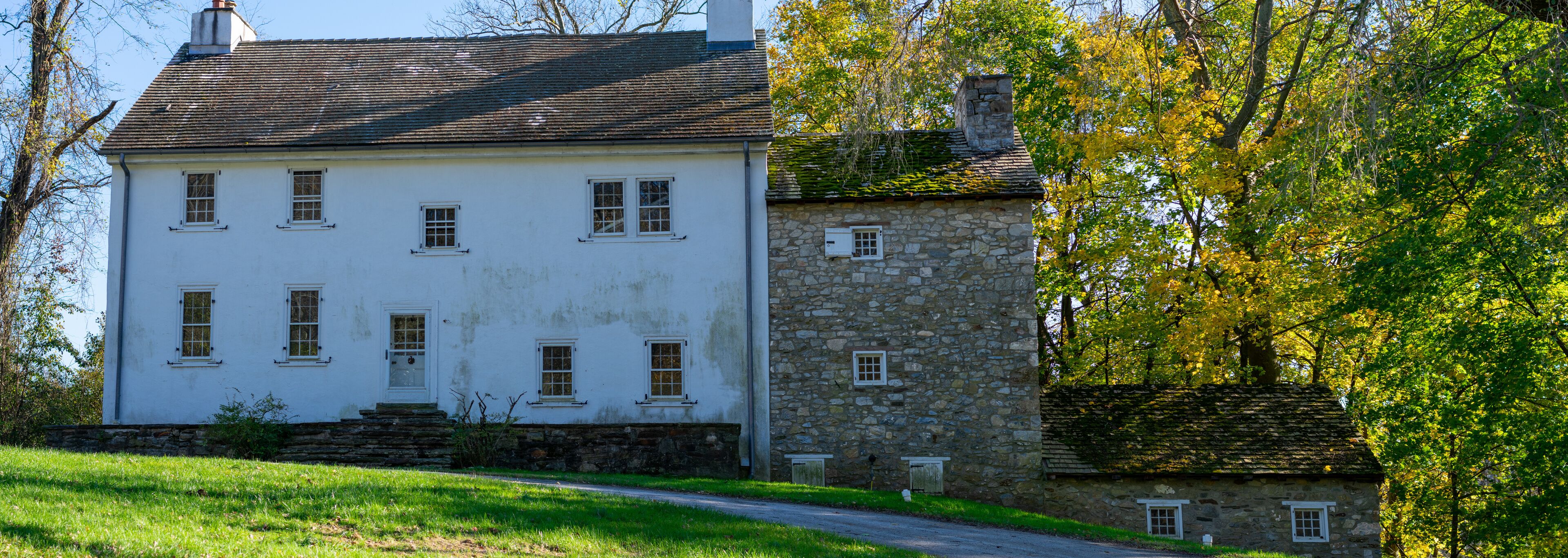 A white house with a stone extension and a stone chimney.
