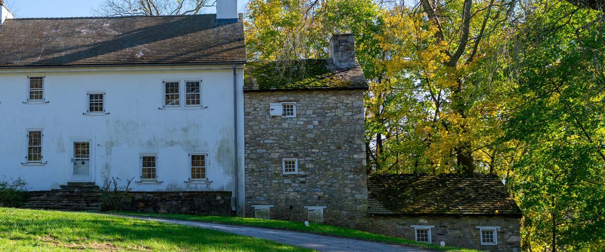 A white house with a stone extension and a stone chimney.