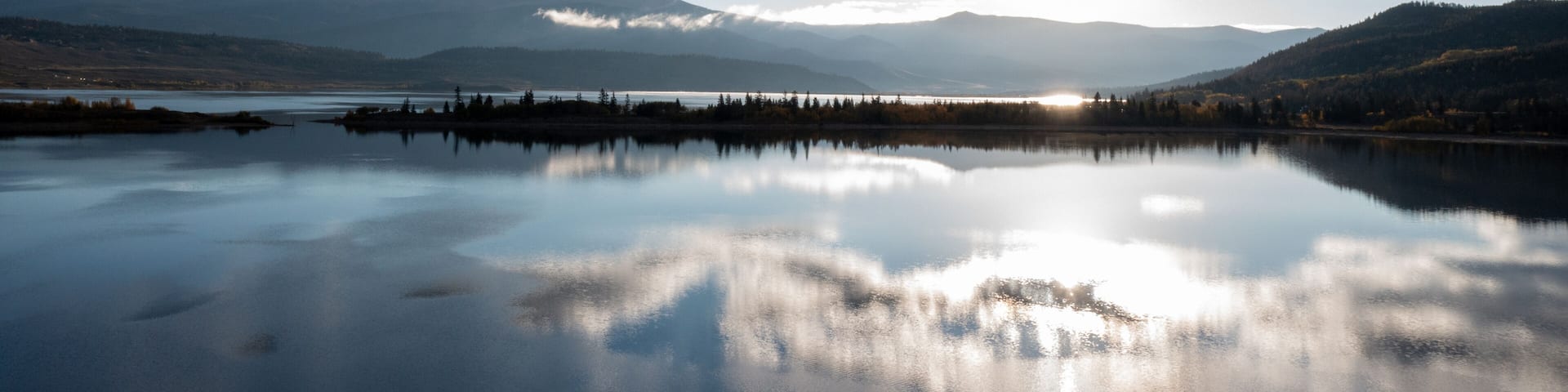A calm lake reflecting the sky and mountains.