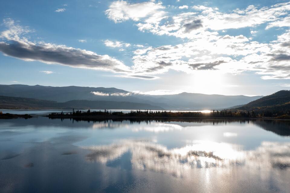 A calm lake reflecting the sky and mountains.