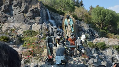 Una estatua imponente de una figura religiosa rodeada de estatuillas y rocas.