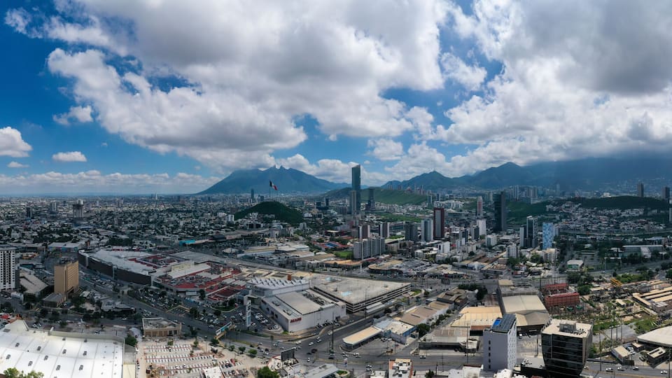 A cityscape with a prominent mountain in the background, dense urban development, and a large open area with industrial buildings.