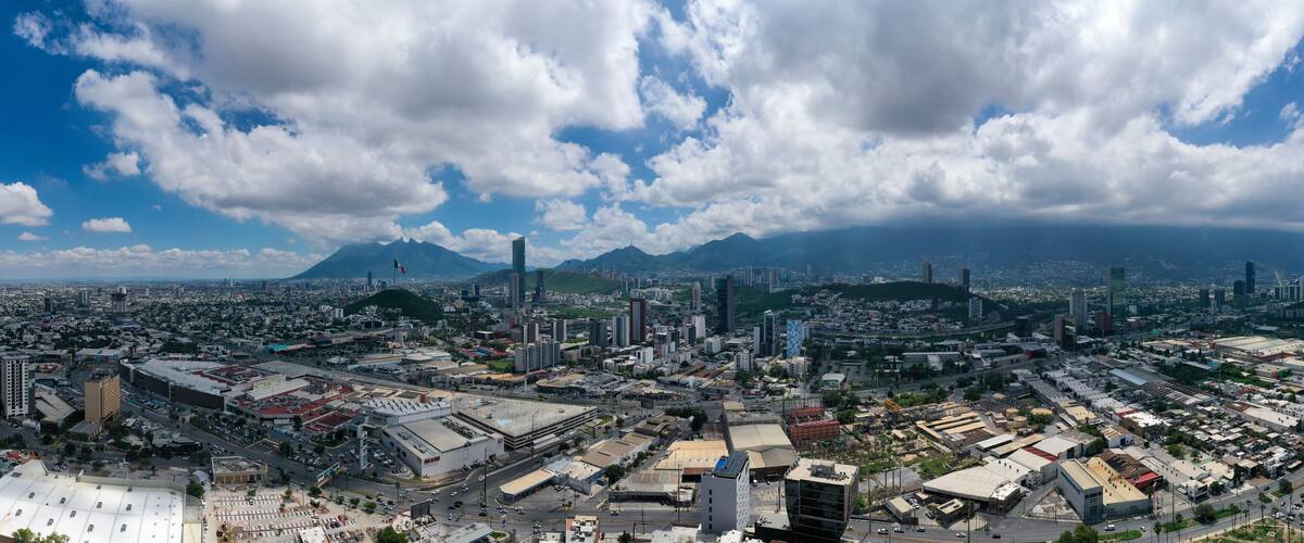 A cityscape with a prominent mountain in the background, dense urban development, and a large open area with industrial buildings.