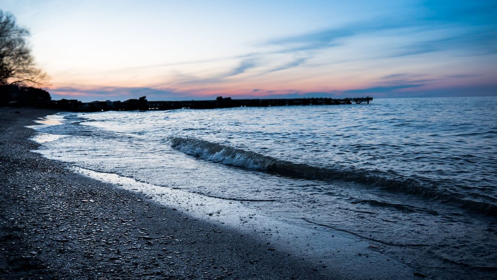 A beach with waves at sunset.