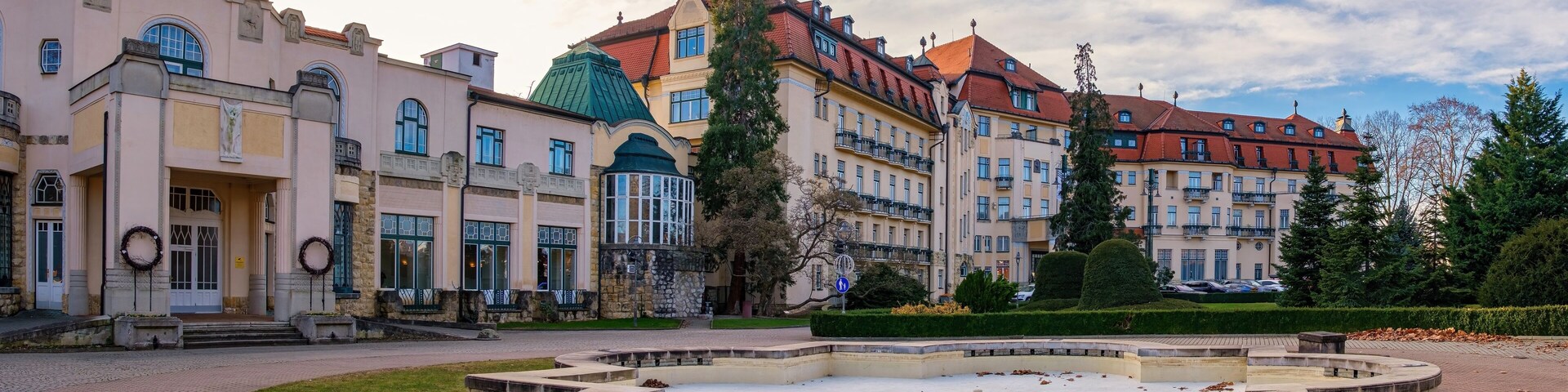 Un complejo de edificios históricos con una fuente al frente.