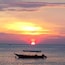A boat on calm waters during sunset with a vibrant sky.