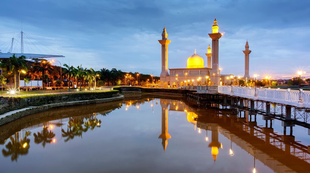 View of Bukit Jelutong Mosque with reflections of the mosque and bridge crossing over the pond during sunrise.