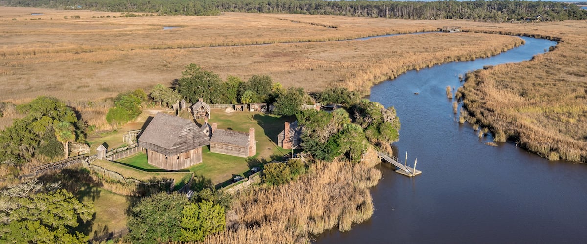 Aerial view of Fort King George historic site, oldest English fort on the Georgia coast from the 17th century with wooden palisade, gun ports for cannons blue cloudy sky near Darien Georgia USA