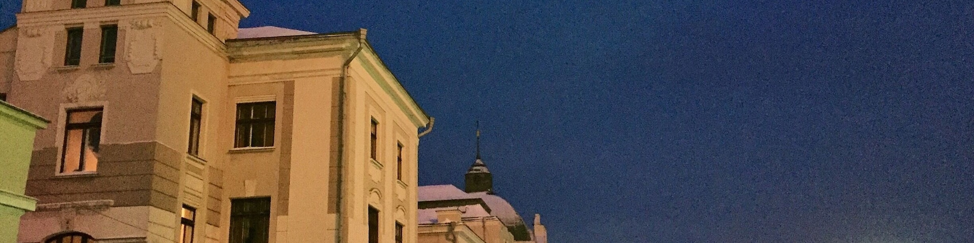 A snow-covered train station at night with a historic building in the background.
