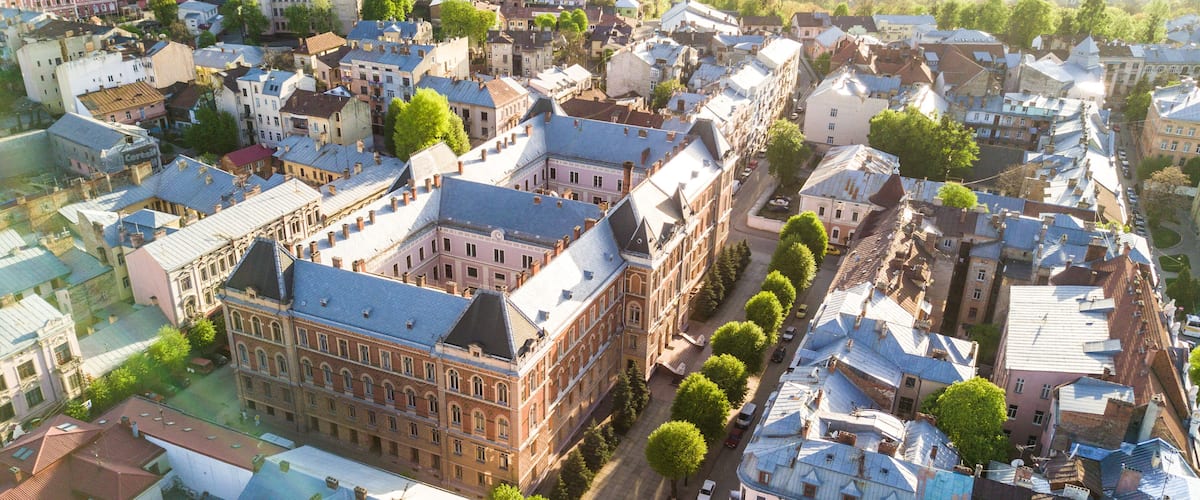 An aerial view of a densely packed urban area with historic buildings, narrow streets, and a prominent large building with a distinctive roof.
