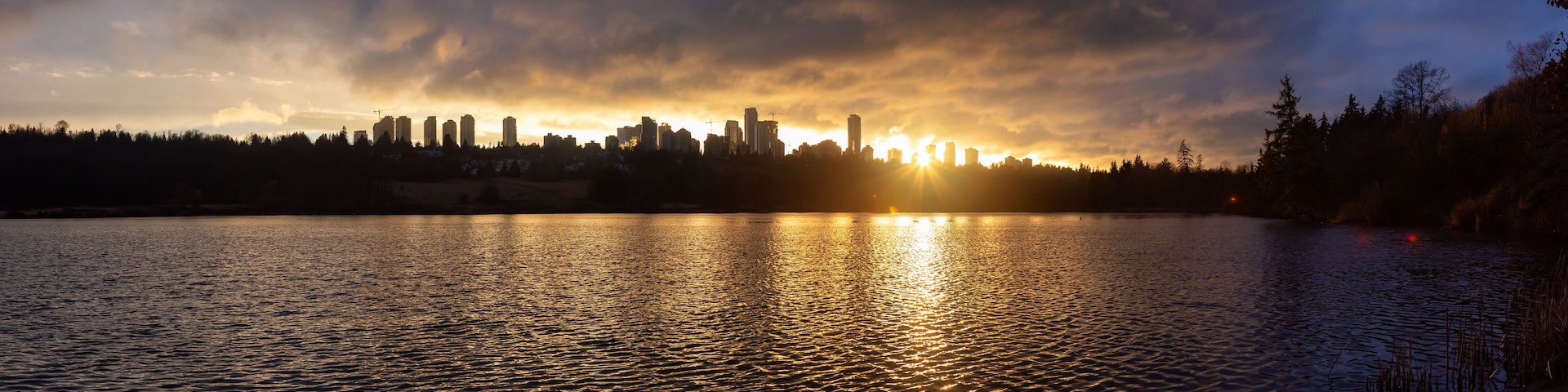 A sunset over a city skyline reflected in a calm body of water.