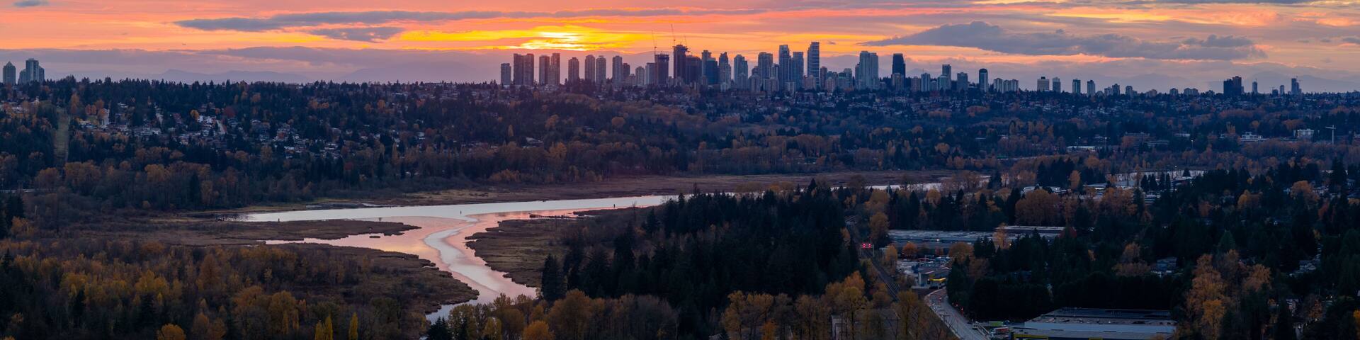 Sunset Over Burnaby Skyline With River, Forest, And City Lights In Greater Vancouver, BC, Canada