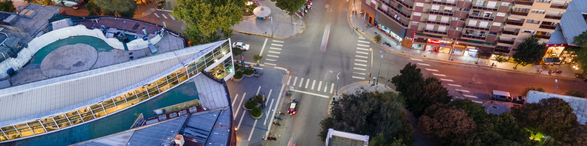 Vue aérienne d’une intersection urbaine, avec des bâtiments, des routes et des arbres.