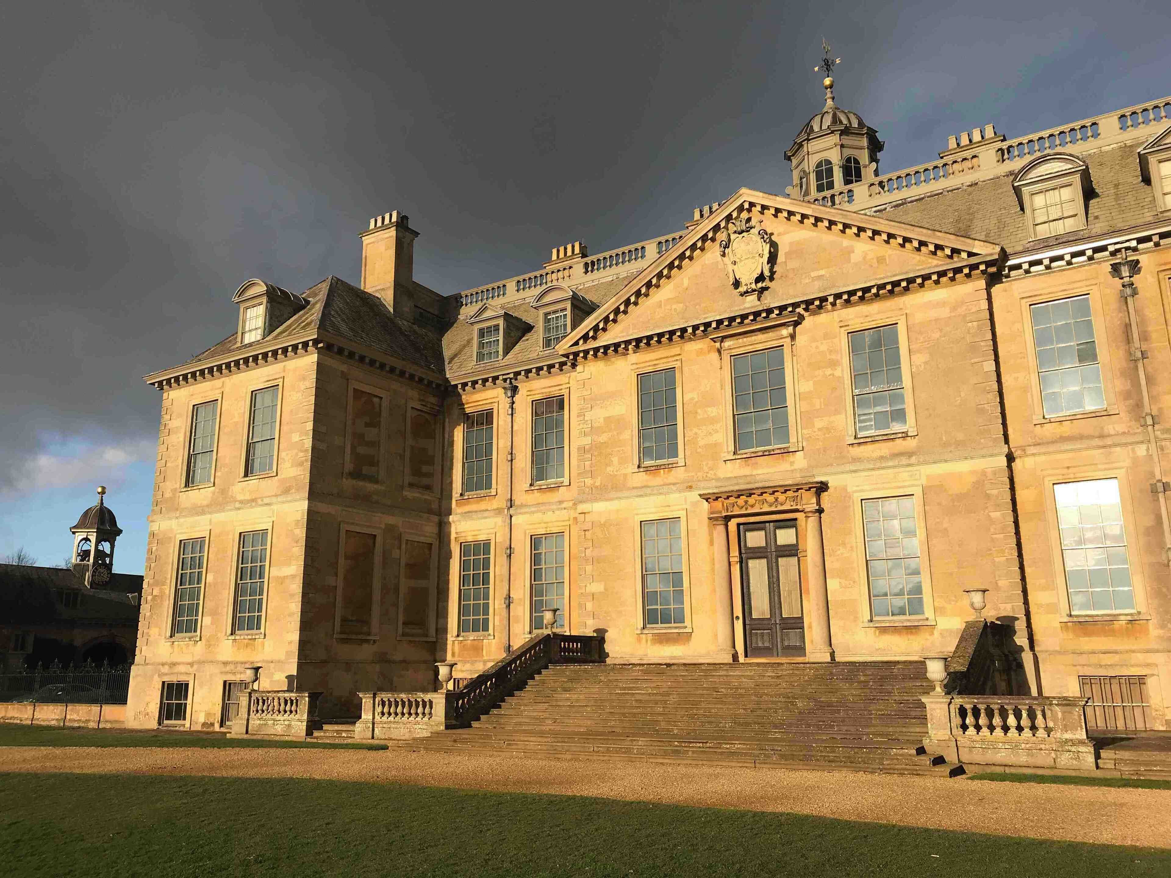 A large, historic building with a prominent entrance, multiple windows, and a clock tower.