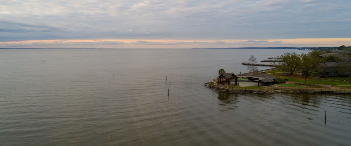 A calm lake with a gazebo and a small pier on the right.