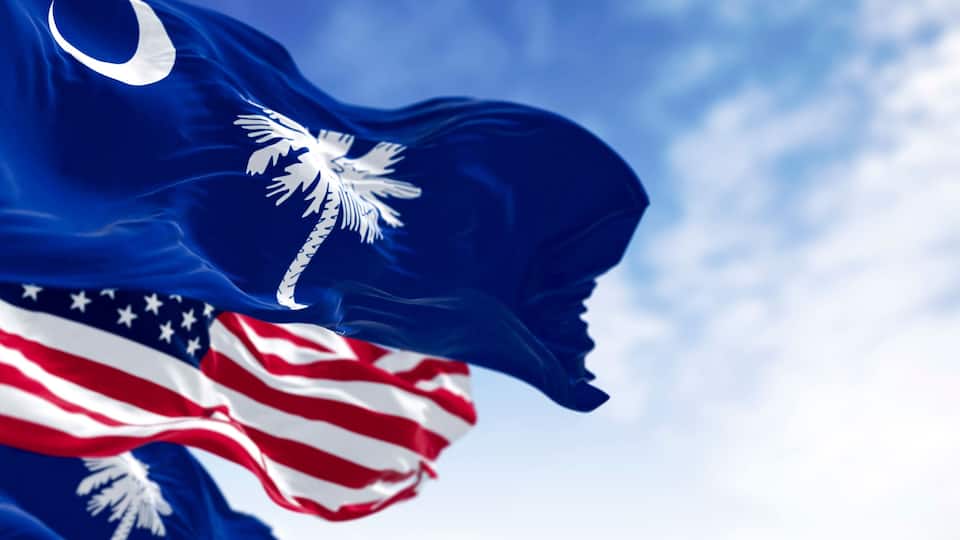 A flag with a blue field and a white emblem, partially obscured by a red and white striped flag.