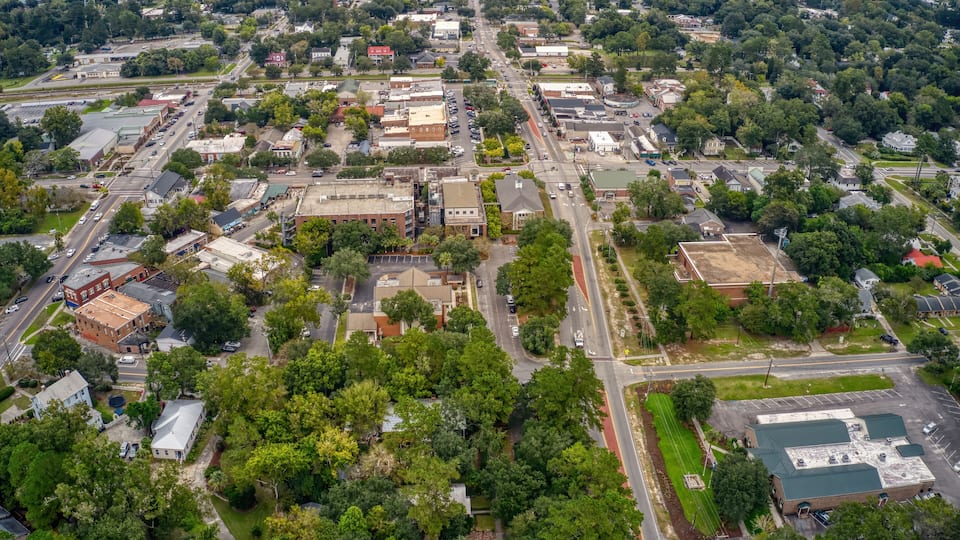 An aerial view of a town with a grid of streets, buildings, and green spaces.