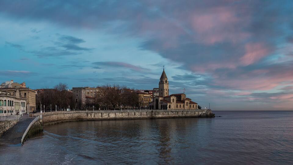 San Pedro church in San Lorenzo beach in Gijon in Asturias natural paradise travel touristic destination for vacations in Spain at dawn before sunrise. Panorama with calm sea landscape background.