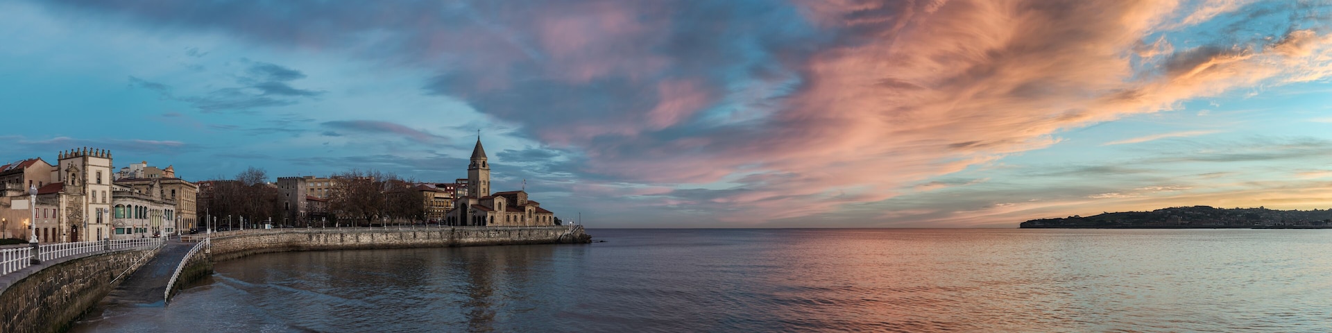 San Pedro church in San Lorenzo beach in Gijon in Asturias natural paradise travel touristic destination for vacations in Spain at dawn before sunrise. Panorama with calm sea landscape background.