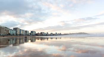 Gijón reflejado en la arena humeda de la playa de San Lorenzo en baja mar . Panorámica de Xixón, Asturias, España.