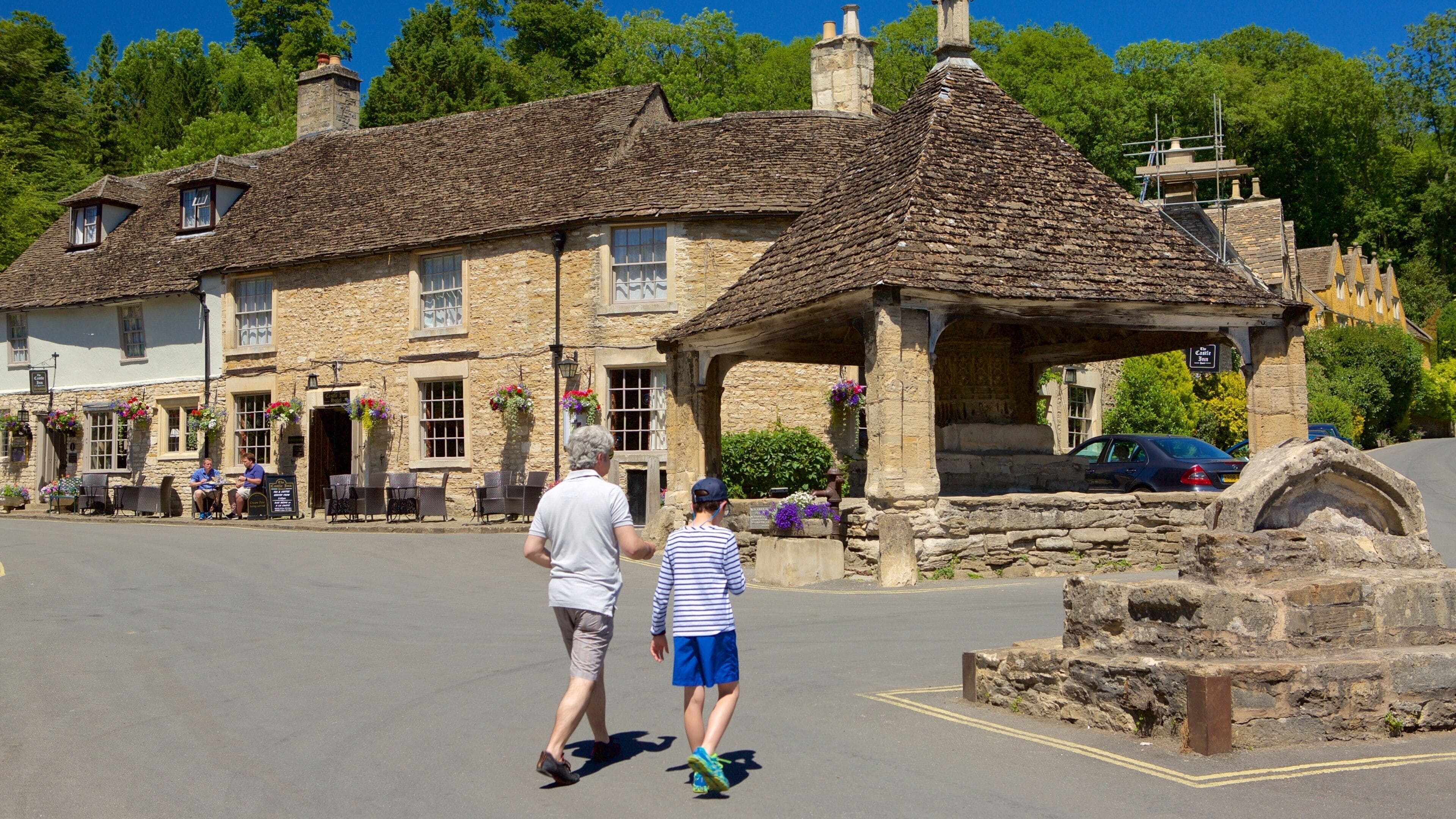 A stone building with a thatched roof, a sign reading "Cottage Inn," and a stone archway.