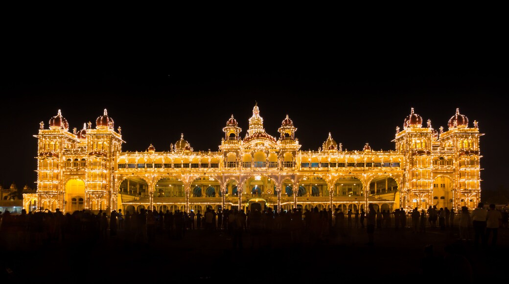 Um edifício ricamente iluminado e ornamentado, com várias cúpulas e arcos, refletindo na água.
