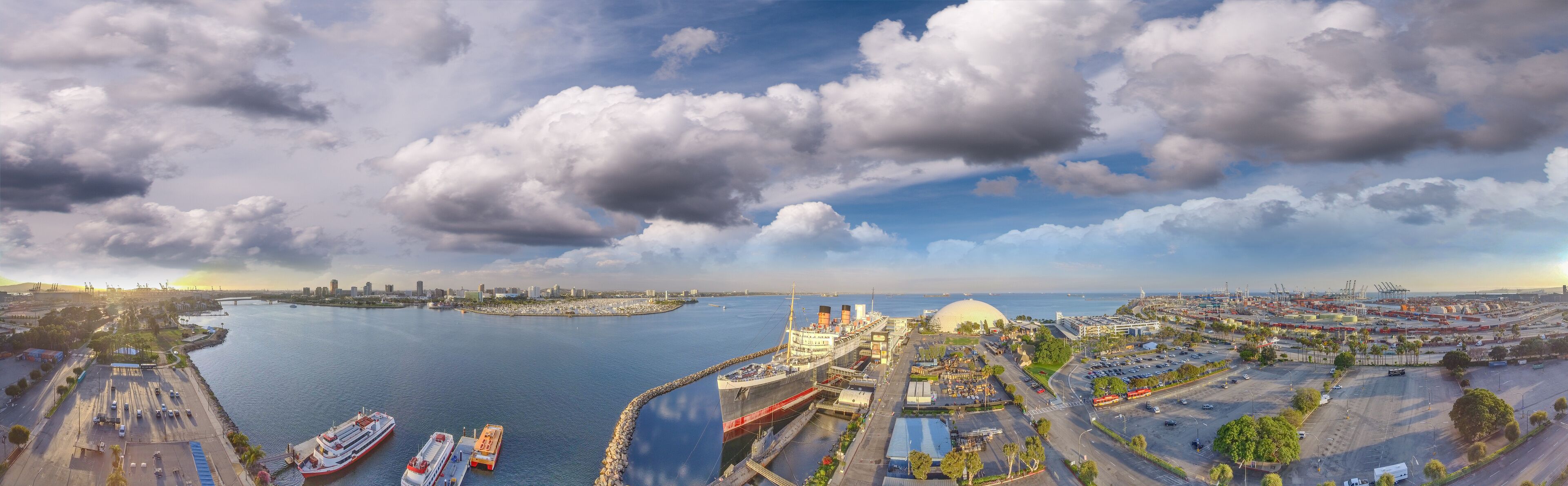 A coastal cityscape with a large body of water, a prominent dome structure, and several ships docked at the port.