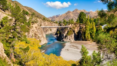 A river flowing through a mountainous landscape with a bridge spanning the river.