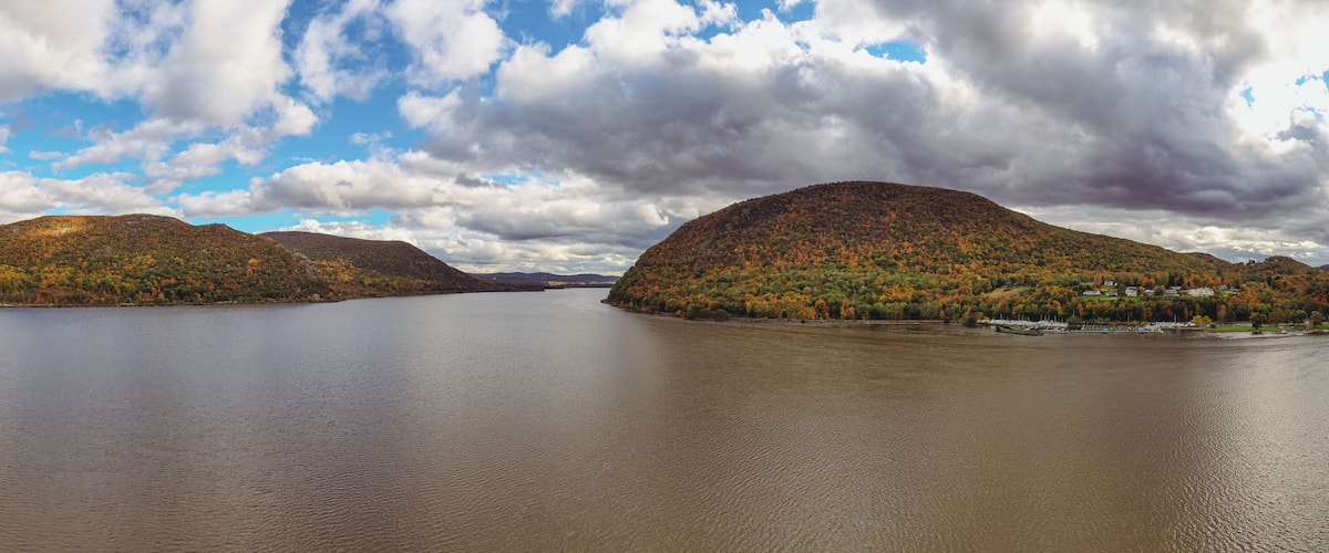 Panoramic view of the Hudson River with autumnal foliage around the mountains at Highland Falls