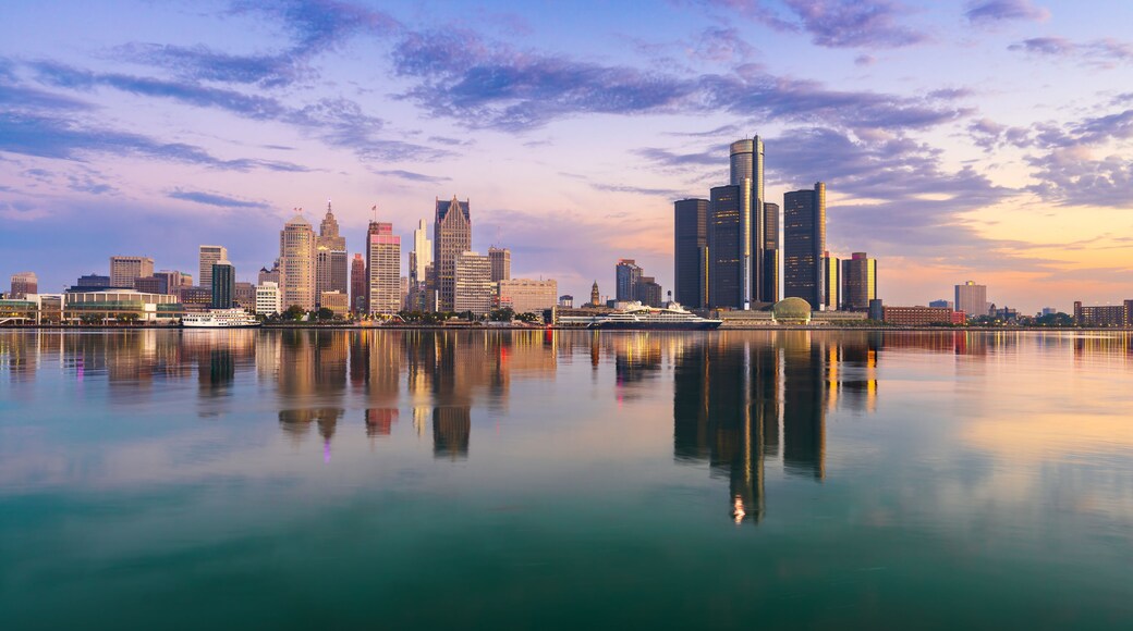 A city skyline reflected in calm waters with a clear sky.