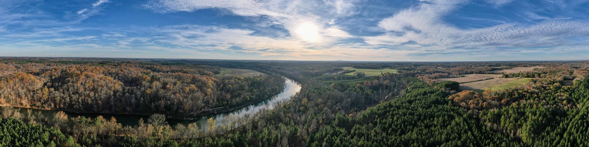 A river winding through a forested valley with a clear sky above.