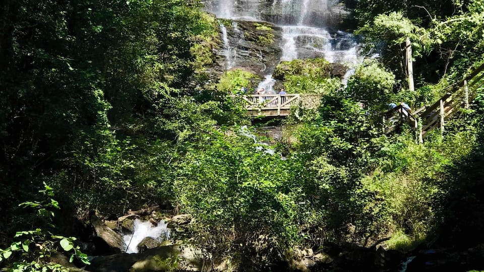 A multi-tiered waterfall surrounded by lush greenery.