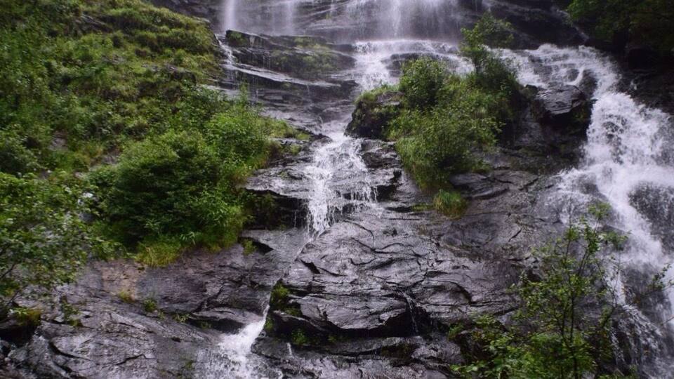 A multi-tiered waterfall surrounded by lush greenery.