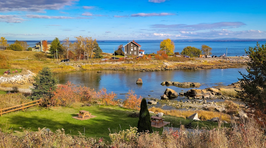 A lakeside landscape with autumn foliage, a stone bridge, and a house with a red roof.