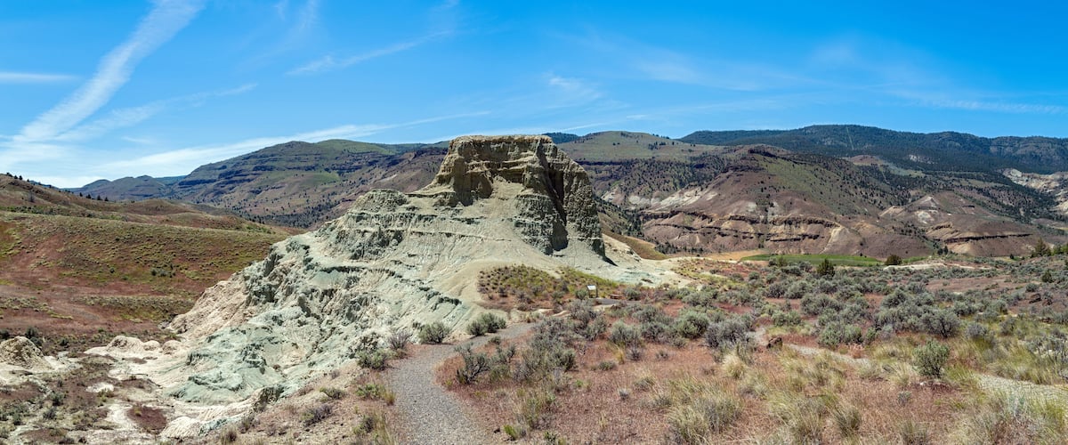 A rugged mountain landscape with a prominent rock formation and a clear blue sky.