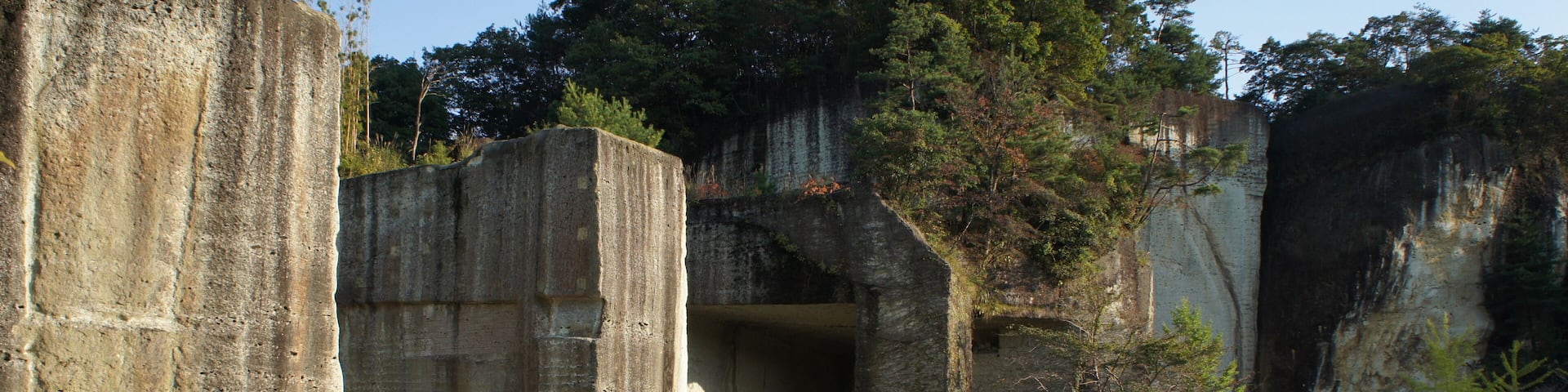 A large concrete structure with a cave-like opening, surrounded by trees and a paved area.