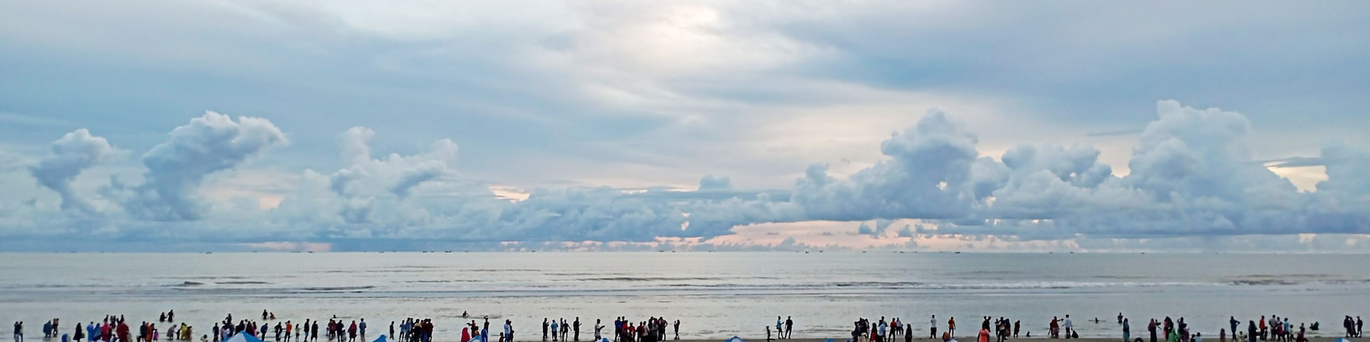 A beach with people, umbrellas, and lounge chairs.