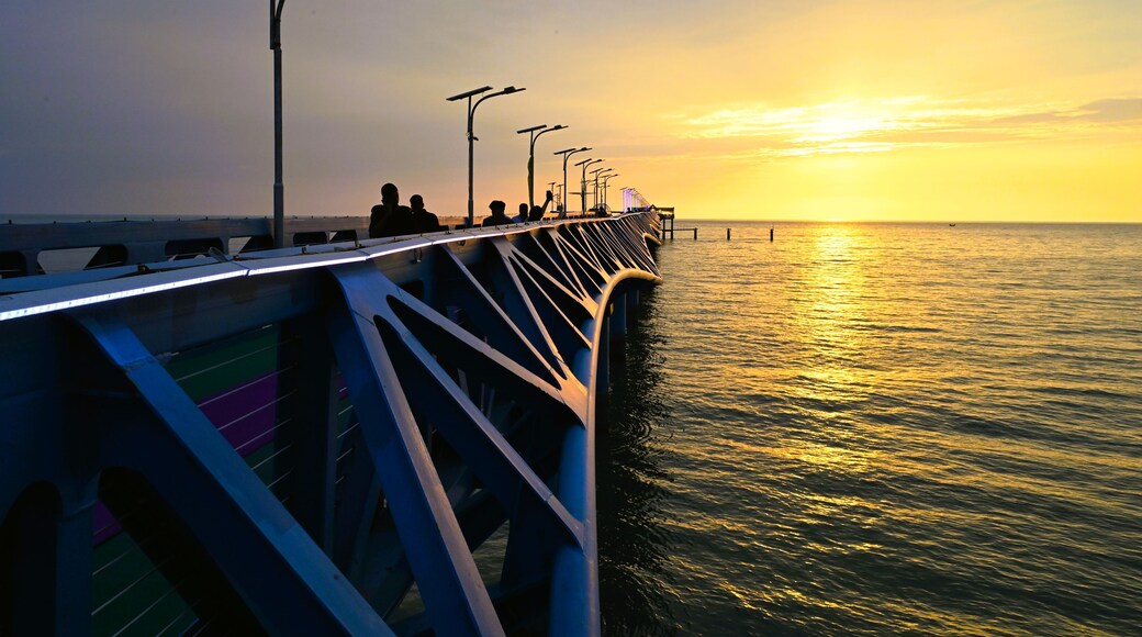 Cox's Bazar District, Chittagong Division, Bangladesh - 14 September 2026: View of the modern metal jetty at Teknaf Beach during a golden sunset, with people walking.