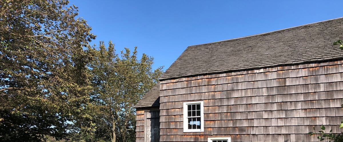 A rustic wooden building with a wooden deck and a fence.